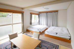 a small room with two beds and a table at Guesthouse Life Field in Kurashiki