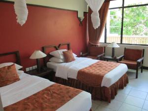 a hotel room with two beds and a window at Indiana Beach Apartments in Bamburi