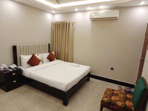Blue Sky Hotel Clifton 2 في كراتشي: غرفة فندق مع سرير وكرسي
