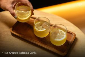 a person is pouring two glasses of orange juice at Hotel Tide Phuket Beachfront in Phuket Town