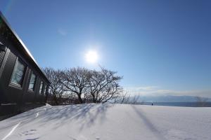 een besneeuwde heuvel met de zon in de lucht bij ホテルカルチャーヴィレッジ in Tomari