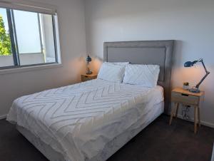 a bedroom with a bed with a white comforter and two windows at Modern & Relaxed Apartment, Great Views @Wright in Weston Creek +7 photos
