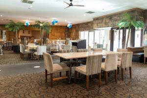 Hamlyn HeightsSphinx Hotel的餐厅里有桌椅和棕榈树