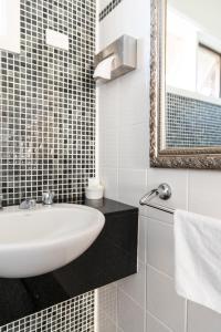 um banheiro branco com uma pia e um espelho em Sphinx Hotel em Hamlyn Heights