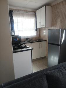 a small kitchen with white cabinets and a refrigerator at Nuday Guesthouse in Vaalwater
