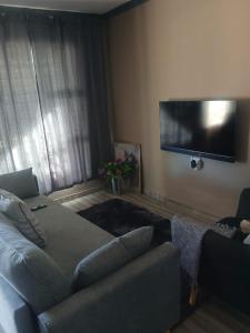 a living room with a couch and a flat screen tv at Nuday Guesthouse in Vaalwater