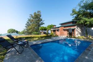a swimming pool with a chair and a house at StayVista at Horizon 4BHK with Breakfast & Valley view in Kasauli