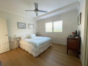 Un dormitorio con una cama y un ventilador de techo. en Cronulla courtyard unit, 10 mins walk to Beach & Bay, en Cronulla