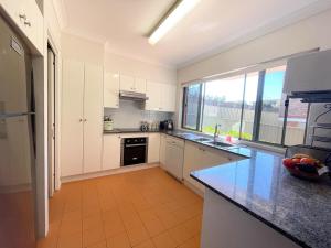 Una cocina con gabinetes blancos y una ventana grande. en Cronulla courtyard unit, 10 mins walk to Beach & Bay, en Cronulla 9 fotos más