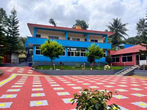 a blue building with a red and white tile courtyard in front at Saatvik Stay 2 - A Dormitory Stay in Kushālnagar +6 photos