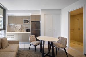 a kitchen and living room with a table and chairs at Meriton Suites Campbell Street, Sydney in Sydney