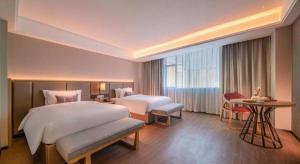 una habitación de hotel con dos camas y una mesa en Echeng Hotel Hezhou Shizheng Square, en Wuzhou 201 fotos más