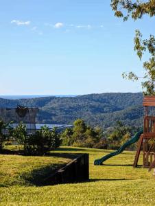 a playground with a green slide in the grass at Coastview Manor - Family Hinterland Retreat in Valdora