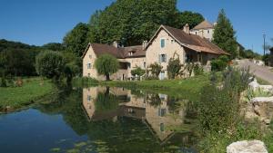 a house next to a river in a village at Les maisons vigneronnes in Ozenay