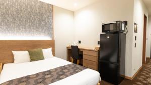 a hotel room with a bed and a desk and a tv at Chiyokura HOTEL SHUKU Nagoya in Nagoya
