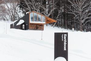 a cabin in the snow with a sign in the foreground at Earthboat Togakushi in Nagano