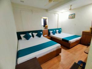 a bedroom with two beds with blue pillows at Hotel shree Tapovan in Ahmedabad