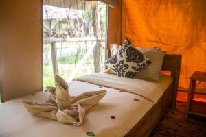 a bed with a towel on it with a window at Africa Safari Selous Camping in Kwangwazi