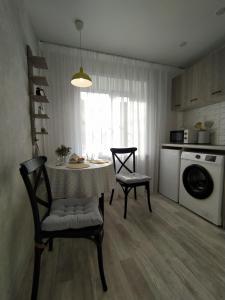 a kitchen with a table and two chairs and a microwave at Уютная однокомнатная квартира в тихом районе in Pavlodar