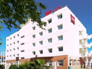a white building with a hotel sign on it at Ibis Barcelona Castelldefels in Castelldefels