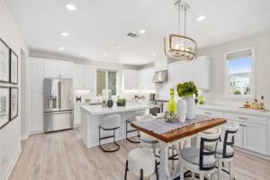 eine weiße Küche mit einem Holztisch und Stühlen in der Unterkunft #Marbella Lane - Chic Stay In Prime Irvine Area in Irvine