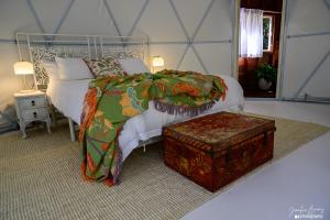 ein Schlafzimmer mit einem Bett und einem daneben stehenden Hocker in der Unterkunft Peaceful off-grid stay surrounded by nature in Traveston