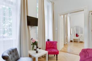 una sala de estar con una silla rosa y una mesa. en Prague Siesta Apartments, en Praga