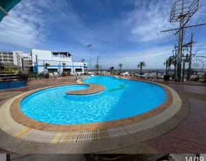 a large blue swimming pool with the ocean in the background at Bangsaen sansuk in Ban Laem Thaen