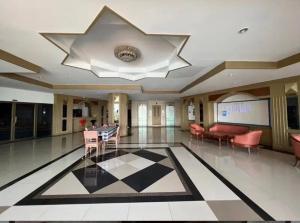 a lobby with a large ceiling with a table and chairs at Bangsaen sansuk in Ban Laem Thaen