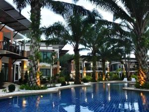 a large swimming pool with palm trees in front of buildings at Nattha Waree Hot Spring Resort and Spa in Ban Hua Khuan
