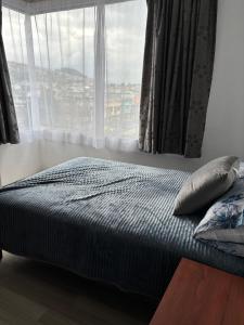 a bed in a bedroom with a large window at Comfortable apartment in South Quito in Quito