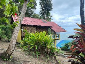 un petit bâtiment avec un toit rouge à côté de l'océan dans l'établissement Mama's Bungalows Koh Chang Ranong, à Koh Chang Ranong 220 autres photos