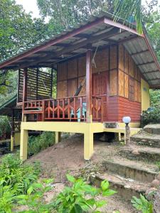 Cette petite maison en bois dispose d'une terrasse couverte et d'escaliers. dans l'établissement Mama's Bungalows Koh Chang Ranong, à Koh Chang Ranong