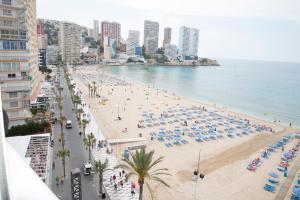 a beach with people and umbrellas and the ocean at Veracruz Alquilevante in Benidorm
