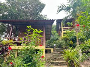 une petite maison avec un banc dans un jardin dans l'établissement Mama's Bungalows Koh Chang Ranong, à Koh Chang Ranong
