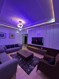 a living room with purple lighting and a couch and a tv at Maas Nightingale Apartments in Port Harcourt