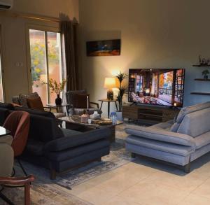 a living room with couches and a flat screen tv at فيلا بمزرعة in Al-ʿUla
