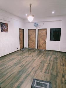 een lege kamer met houten vloeren en deuren bij SHiVAY HOMESTAY in Garudeshwar