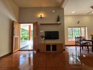 a living room with a television and a dining room at Acrewood Farmhouse - Pool Villa in Vāzhākulam