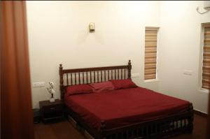 a bedroom with a bed with a red blanket at Acrewood Farmhouse - Pool Villa in Vāzhākulam +14 photos