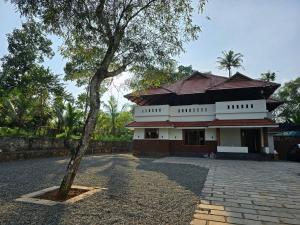a building with a tree in front of it at Acrewood Farmhouse - Pool Villa in Vāzhākulam