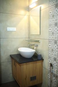 a bathroom with a white sink and a mirror at Acrewood Farmhouse - Pool Villa in Vāzhākulam
