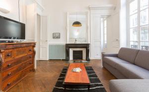 a living room with a couch and a tv and a fireplace at Opéra Septembre in Paris