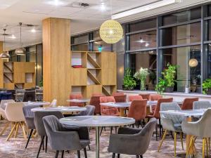 un restaurante con mesas, sillas y ventanas en Novotel Kraków Centrum, en Cracovia 186 fotos más