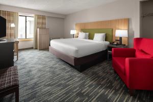 a hotel room with a bed and a red couch at Wingate by Wyndham Lincoln Airport East I-80 in Lincoln +78 photos