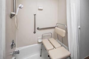 a bathroom with a chair and a shower at Wingate by Wyndham Lincoln Airport East I-80 in Lincoln +76 photos