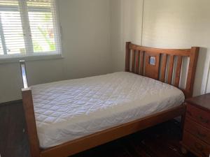 a bedroom with a bed with a wooden frame and a window at The Beach Cottage - close to beach and river mouth in Guilderton