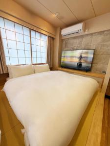 a bedroom with a large white bed and a flat screen tv at Rakuyu asakusa in Tokyo