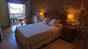 a bedroom with a bed and a stone wall at Apartamentos Rurales Pedredo in Pedredo