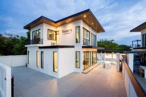 une grande maison blanche avec beaucoup de fenêtres dans l'établissement Walters House Pool Villa Pattaya, à Ban Huai Yai